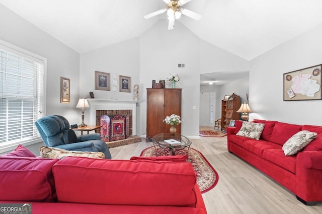 living room with a fireplace, ceiling fan, light hardwood / wood-style flooring, and vaulted ceiling