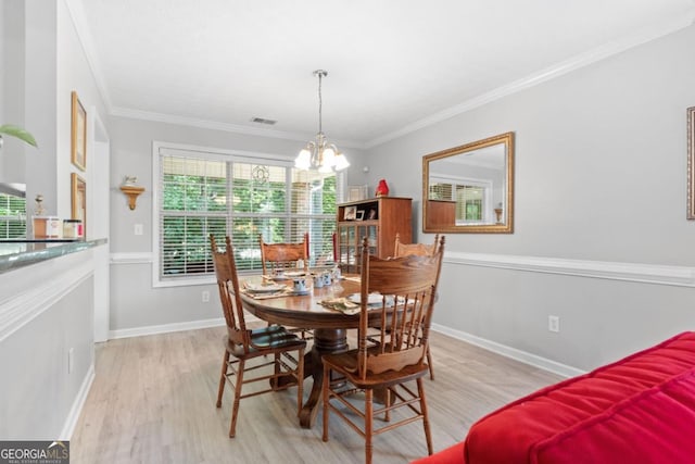 dining room with a chandelier, ornamental molding, and light wood-type flooring