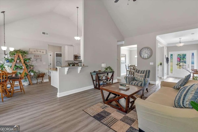 living room with ceiling fan, light hardwood / wood-style floors, ornamental molding, and high vaulted ceiling