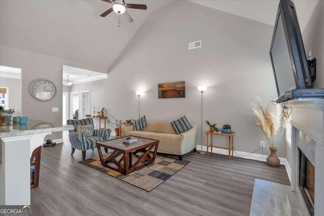 living room featuring a fireplace, dark hardwood / wood-style floors, high vaulted ceiling, and ceiling fan