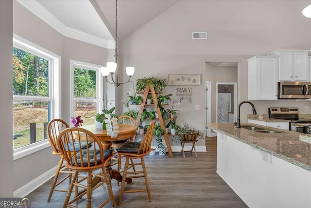 dining room featuring lofted ceiling, sink, plenty of natural light, and an inviting chandelier