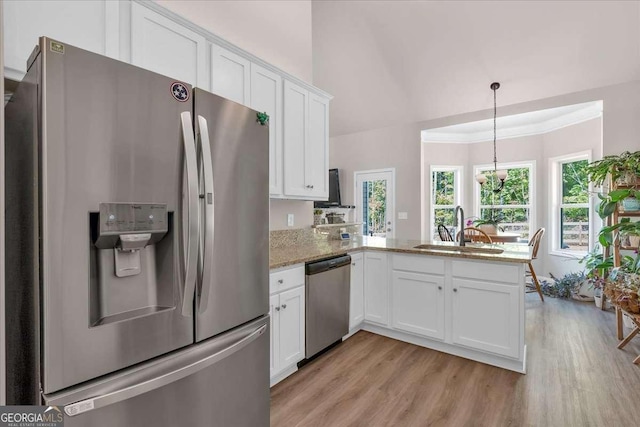 kitchen with white cabinetry, sink, hanging light fixtures, stainless steel appliances, and kitchen peninsula