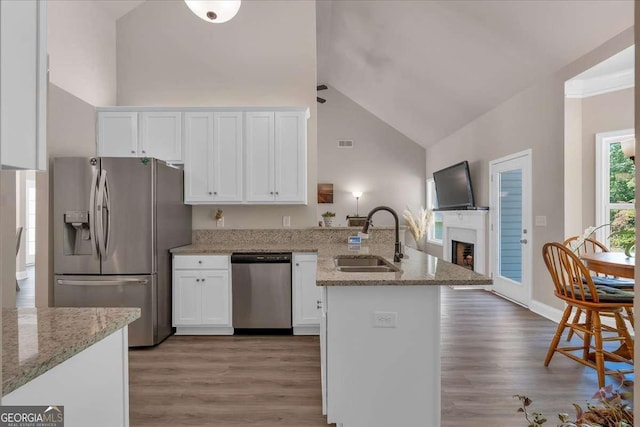 kitchen featuring light stone counters, stainless steel appliances, sink, white cabinets, and hardwood / wood-style floors