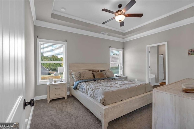 carpeted bedroom featuring ensuite bathroom, ceiling fan, a raised ceiling, and multiple windows