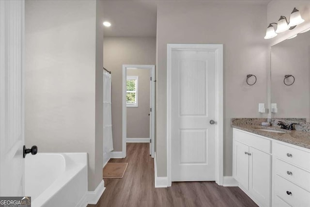 bathroom featuring hardwood / wood-style flooring, vanity, and a tub to relax in