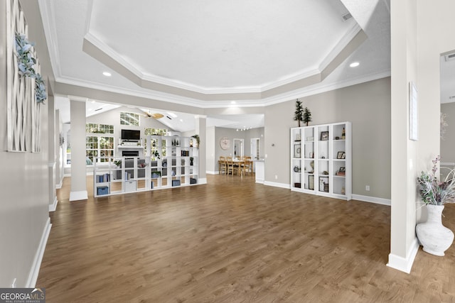 unfurnished living room with crown molding, a raised ceiling, and wood finished floors