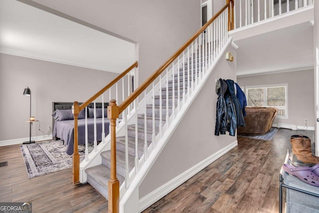 stairs with crown molding and hardwood / wood-style floors