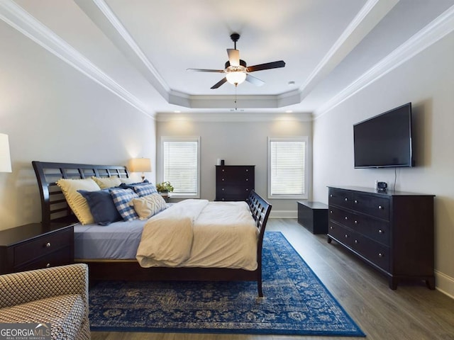 bedroom with ceiling fan, a raised ceiling, dark wood-type flooring, and crown molding