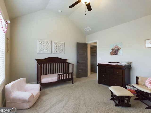 carpeted bedroom featuring vaulted ceiling, a nursery area, and ceiling fan