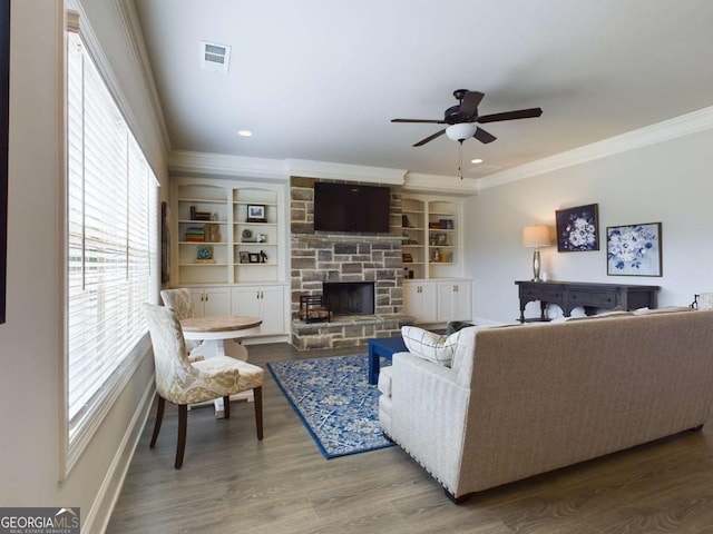 living room with built in shelves, ceiling fan, a healthy amount of sunlight, a fireplace, and hardwood / wood-style floors