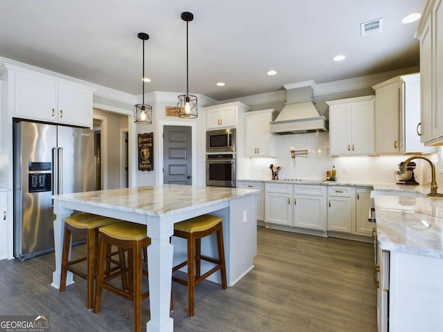 kitchen featuring white cabinets, appliances with stainless steel finishes, premium range hood, and tasteful backsplash