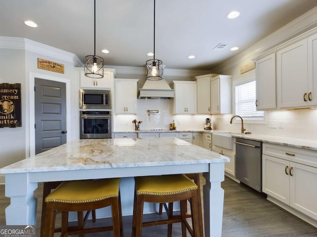 kitchen with decorative light fixtures, a kitchen island, sink, and stainless steel appliances