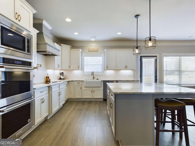 kitchen featuring sink, decorative backsplash, appliances with stainless steel finishes, decorative light fixtures, and white cabinetry