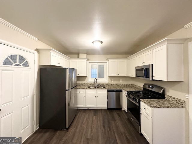 kitchen with dark stone counters, white cabinets, sink, dark hardwood / wood-style floors, and appliances with stainless steel finishes