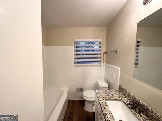 bathroom featuring vanity, a bath, toilet, tile walls, and wood-type flooring