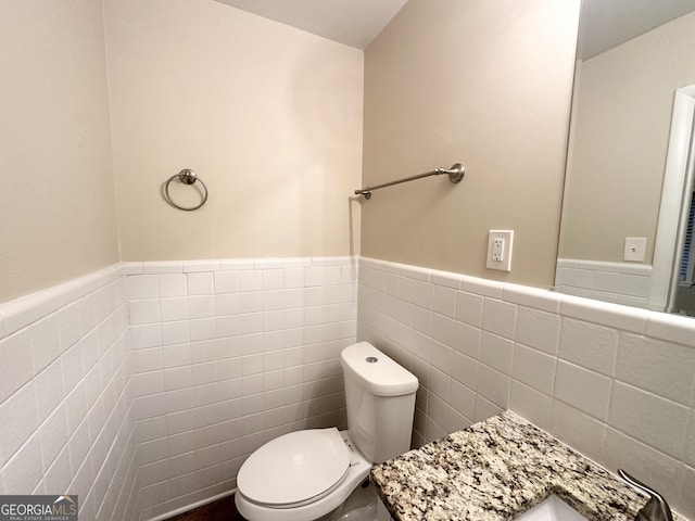 bathroom featuring toilet and tile walls