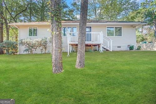 rear view of property with a wooden deck and a yard