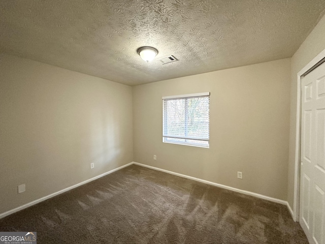 unfurnished bedroom featuring a textured ceiling and dark carpet