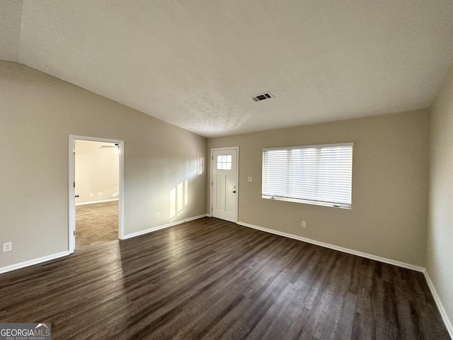 interior space featuring a textured ceiling, lofted ceiling, and dark wood-type flooring