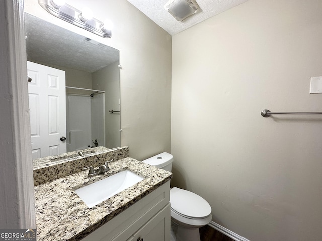 bathroom with vanity, a textured ceiling, and toilet