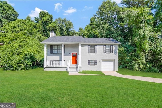 bi-level home with covered porch, a garage, and a front yard