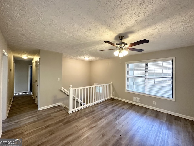 unfurnished room featuring ceiling fan, dark hardwood / wood-style flooring, and a textured ceiling