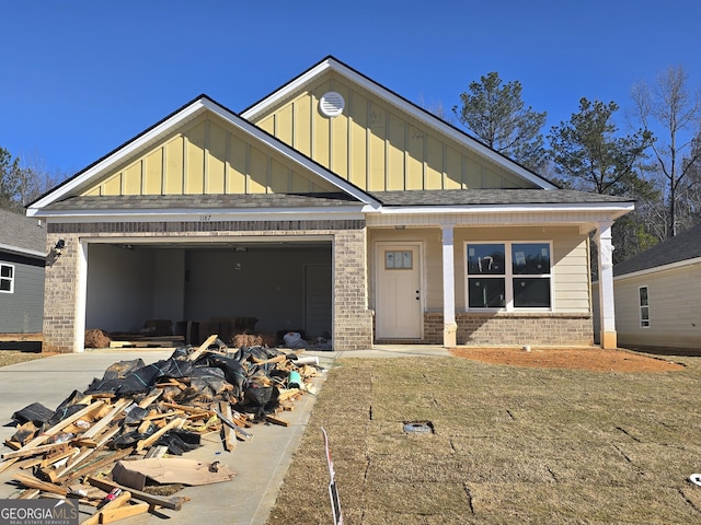 view of front facade featuring a garage, brick siding, board and batten siding, and driveway