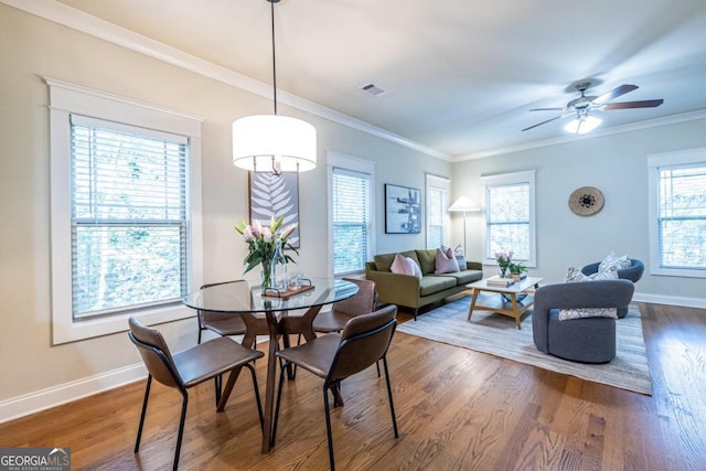 dining space with ceiling fan, a healthy amount of sunlight, ornamental molding, and dark wood-type flooring