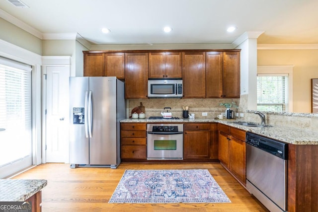 kitchen with sink, crown molding, decorative backsplash, light stone countertops, and stainless steel appliances