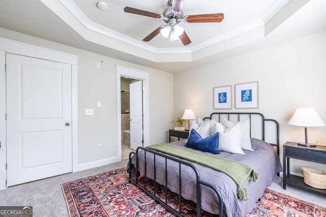 carpeted bedroom featuring ceiling fan, a raised ceiling, ornamental molding, and ensuite bathroom