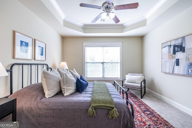 carpeted bedroom with ceiling fan, crown molding, and a tray ceiling