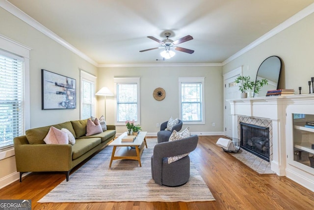 living room featuring hardwood / wood-style flooring, crown molding, and a tiled fireplace