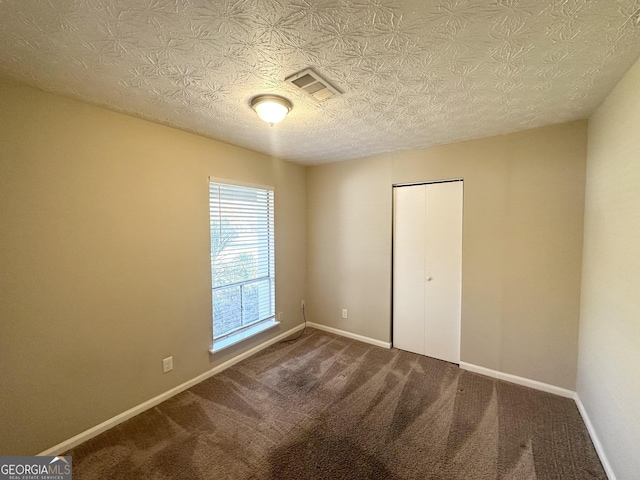 unfurnished room with carpet floors and a textured ceiling