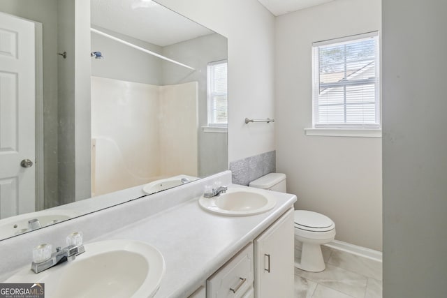 full bath with baseboards, a sink, toilet, and double vanity