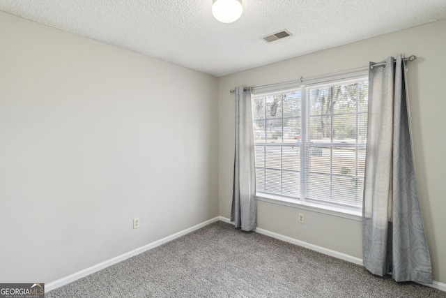 carpeted spare room featuring baseboards, visible vents, and a textured ceiling