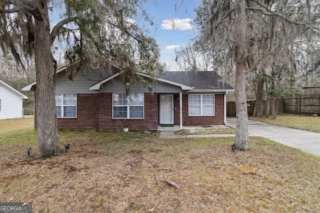 view of front facade with driveway, fence, a front lawn, and brick siding