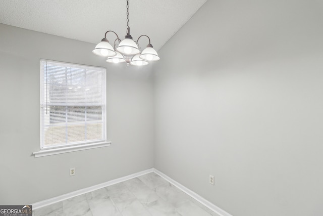 unfurnished dining area with marble finish floor, a textured ceiling, baseboards, and a notable chandelier