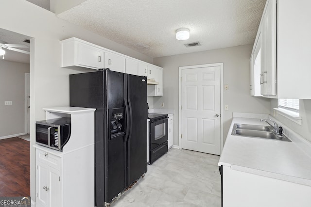 kitchen featuring white cabinets, light countertops, a sink, and black appliances