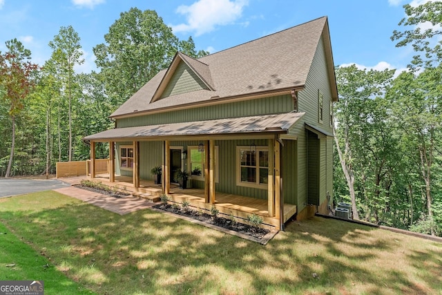 rear view of property with covered porch and a yard