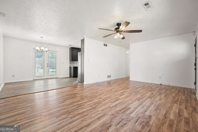 unfurnished living room with a textured ceiling, hardwood / wood-style floors, and ceiling fan with notable chandelier