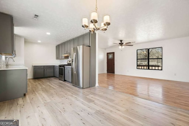 kitchen featuring gray cabinetry, stainless steel appliances, a textured ceiling, ceiling fan with notable chandelier, and light wood-type flooring