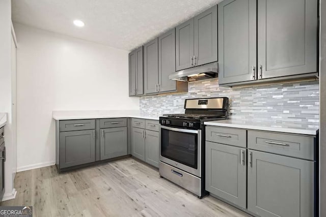 kitchen with gray cabinetry, backsplash, light hardwood / wood-style flooring, and gas range