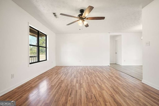 empty room with hardwood / wood-style floors, ceiling fan, and a textured ceiling