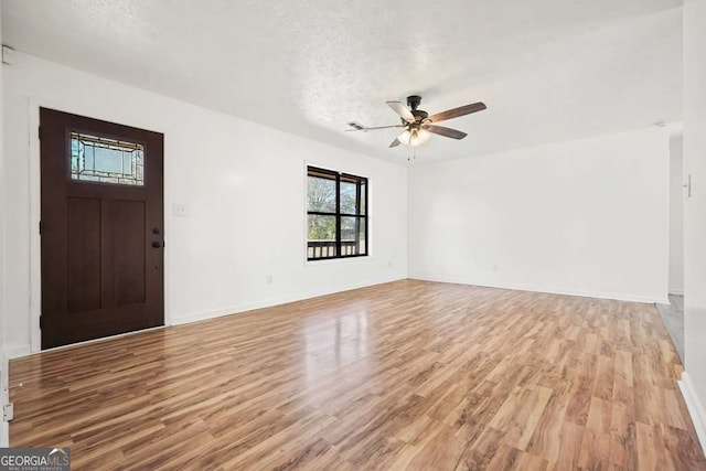 entryway with ceiling fan, light wood-type flooring, and a textured ceiling