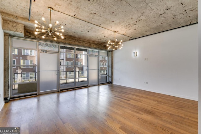 unfurnished room with hardwood / wood-style floors, a wall of windows, and an inviting chandelier