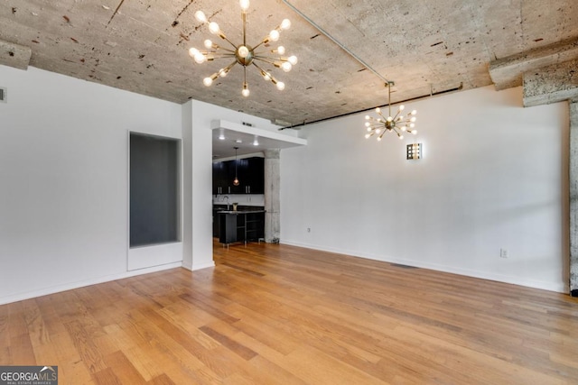 unfurnished living room with wood-type flooring and a notable chandelier