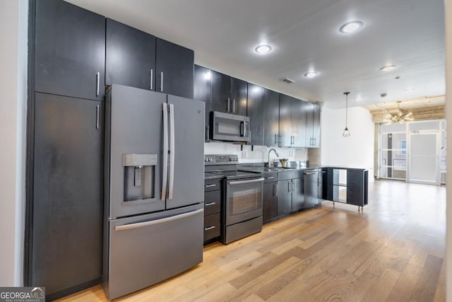 kitchen with sink, light hardwood / wood-style flooring, decorative light fixtures, stainless steel appliances, and a chandelier