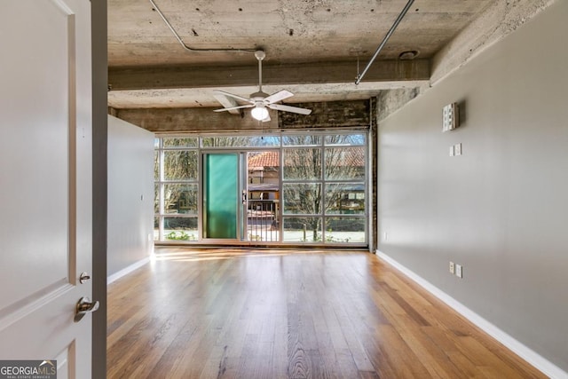 empty room featuring floor to ceiling windows, hardwood / wood-style flooring, and ceiling fan