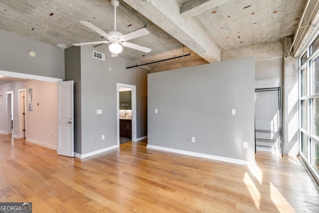 unfurnished living room with a high ceiling, light hardwood / wood-style floors, and ceiling fan