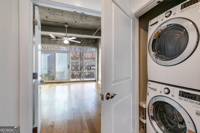 clothes washing area featuring ceiling fan, stacked washer and clothes dryer, and hardwood / wood-style flooring